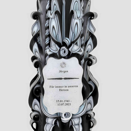 handgeschnitzte schwarze Kerze mit kunstvollem Schnitzdesign. Innenschichten sind in hellblau-grau gestaltet. Unten mittig ist ein personalisiertes Schild sichtbar