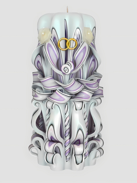 Handgefertigte, kunstvoll geschnitzte Hochzeitskerze in Weiß und zarten Lavendeltönen, dekoriert mit goldenen Eheringen und kleinen Kunstblumen.