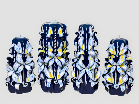 Vier handgeschnitzte Kerzen mit eleganten blauen, weißen und gelben Mustern auf hellgrauem Hintergrund