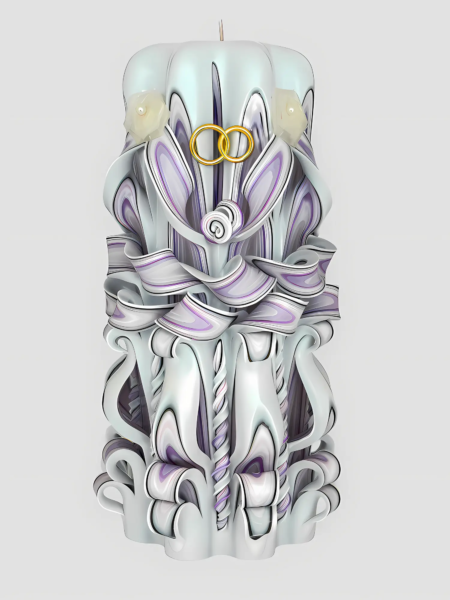 Handgefertigte, kunstvoll geschnitzte Hochzeitskerze in Weiß und zarten Lavendeltönen, dekoriert mit goldenen Eheringen und kleinen Kunstblumen.