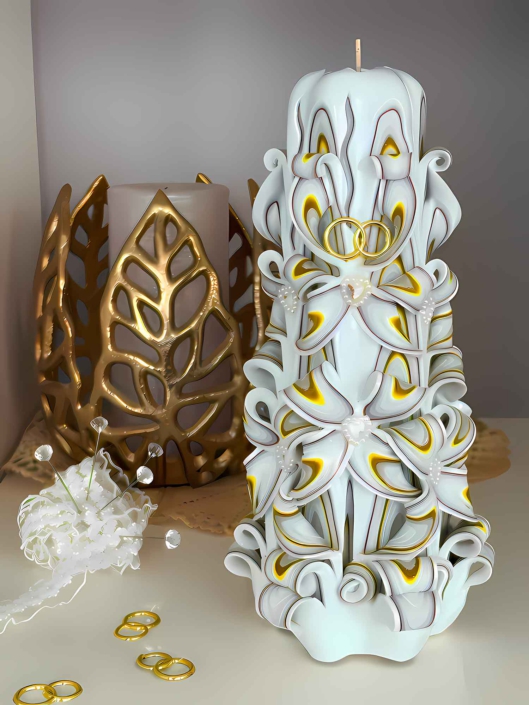 Hochzeitskerze in weiß-gold mit dekorativen Eheringen.