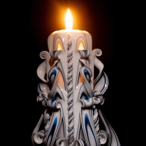 weiße handgeschnitzte Kerze ist angezündet und leuchtet durch jeden Schnitt