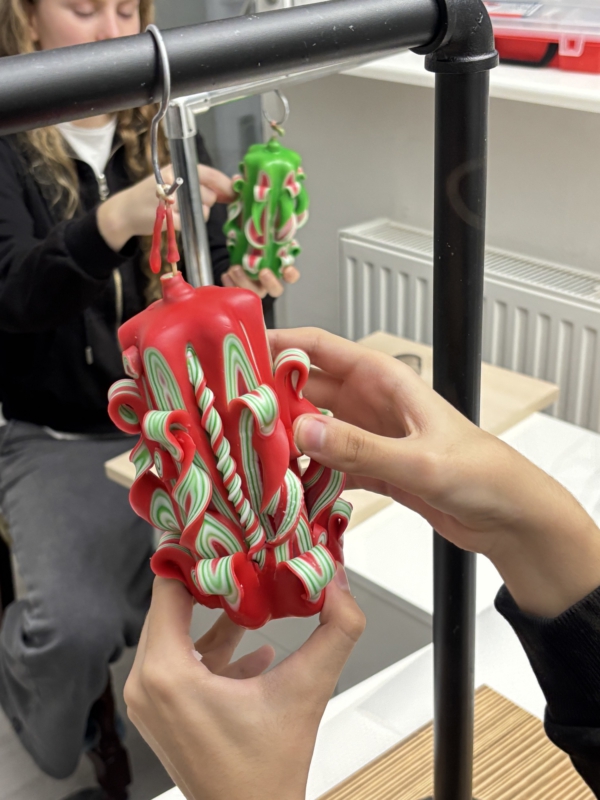 Kinder gestalten bunte Kerzen, Rote handgeschnitzte Kerze h&auml;ngt auf dem Schnitztisch