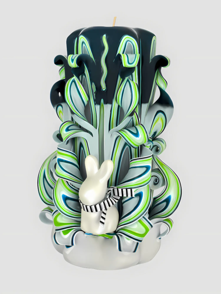 Handgeschnitzte Designkerze in Grün-, Blau- und Weißtönen mit plastischem Osterhasen auf der Vorderseite, der eine schwarz-weiß gestreifte Schleife trägt.