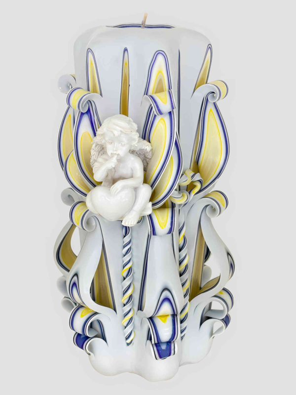 Gro&szlig;e handgefertigte wei&szlig;e Kerze mit zentraler wei&szlig;er Engelfigur, umgeben von gelb-blauen floralen Schnitzmustern vor hellem Hintergrund