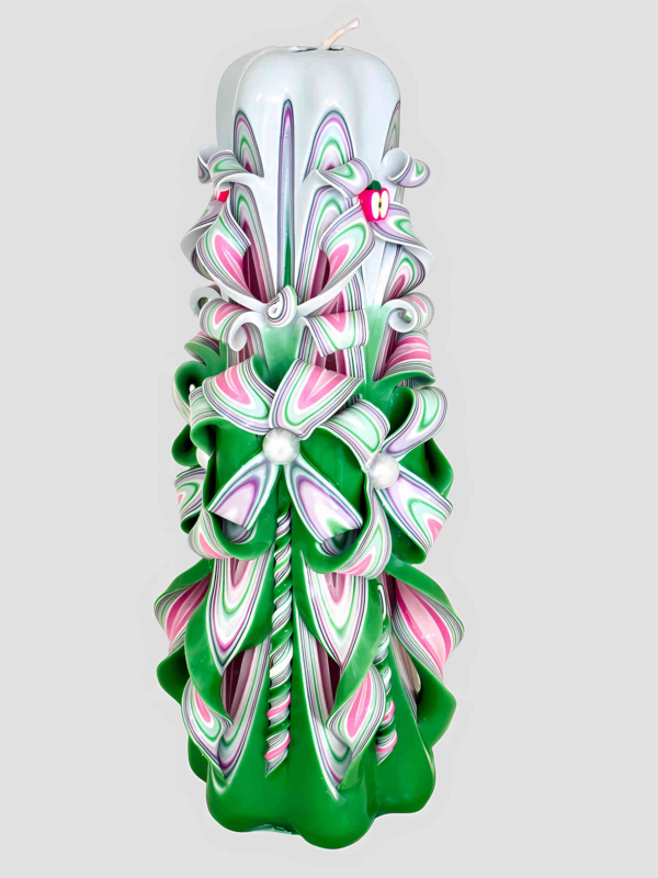 Handgeschnitzte gr&uuml;ne Kerze mit wei&szlig;en, rosa und lilafarbenen floralen Verzierungen sowie einem roten Apfel oben