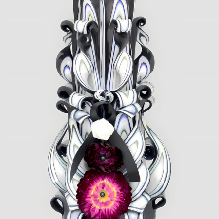 Handgeschnitzte schwarze Trauerkerze mit weißen und blauen Wellenmustern sowie zentraler pinkfarbener Blume vor hellem Hintergrund.