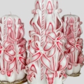 Drei Handgeschnitzte Kerzen in Weiß-Rot. Schnittdesign als Blume. In der Mitte eine größere Kerze, links und rechts kleinere Kerzen, gleicher Höhe